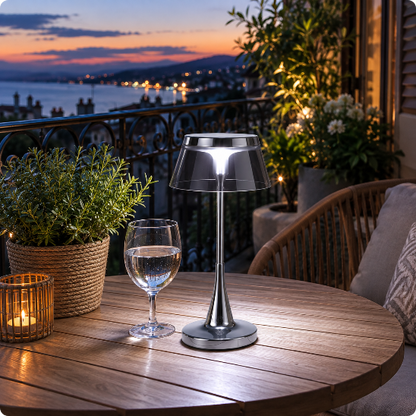 lampe de table Prisma gris fumé éclairant une table sur un balcon