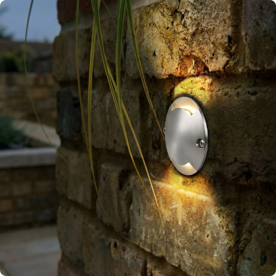 Spot à led extérieur Véga argent 2 côtés posé sur un mur en pierres
